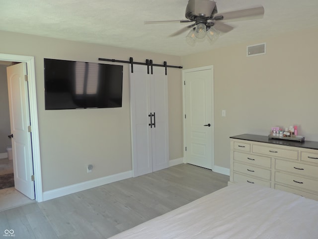 282 W Santee Dr, Greensburg, IN 47240 - bedroom featuring light wood-type flooring, baseboards, a barn door, and a ceiling fan