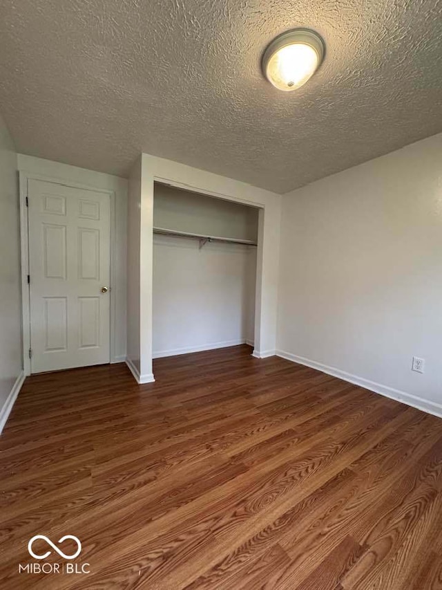 7833 Broadview Dr, Indianapolis, IN 46227 - unfurnished bedroom featuring a textured ceiling, a closet, baseboards, and dark wood-style flooring