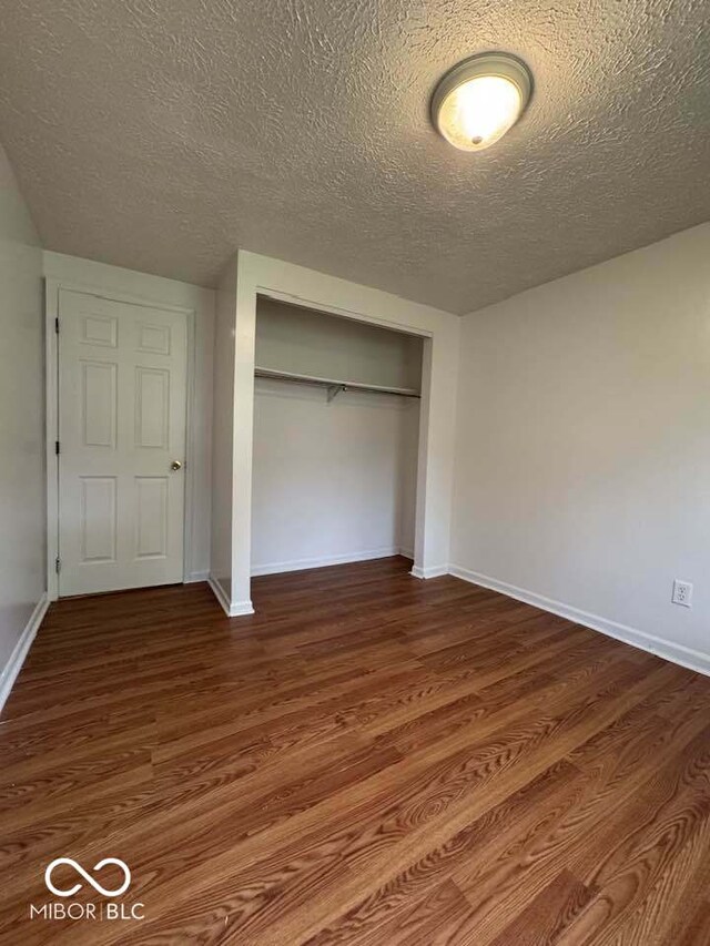 7833 Broadview Dr, Indianapolis, IN 46227 - unfurnished bedroom featuring baseboards, dark wood-style flooring, a textured ceiling, and a closet