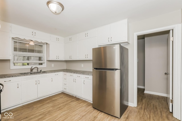 9535 E Michigan St, Indianapolis, IN 46229 - kitchen featuring white cabinetry, a sink, light wood-style flooring, and freestanding refrigerator
