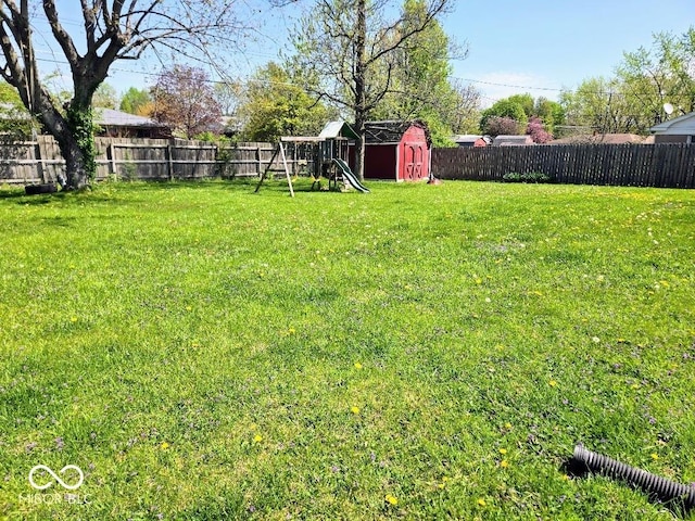 8230 E 11th St, Indianapolis, IN 46219 - view of yard featuring a storage unit, a fenced backyard, and a playground