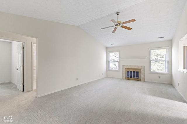 unfurnished living room with ceiling fan, visible vents, a fireplace, lofted ceiling, and light carpet