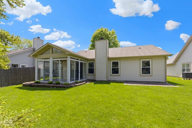 back of property with fence, cooling unit, a chimney, a sunroom, and a lawn