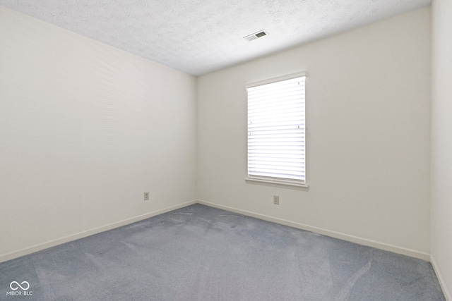 spare room with visible vents, a textured ceiling, baseboards, and carpet floors