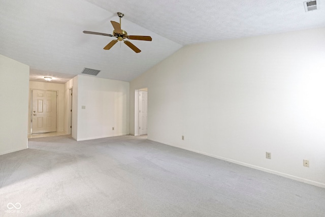 empty room featuring visible vents, a ceiling fan, vaulted ceiling, and light carpet