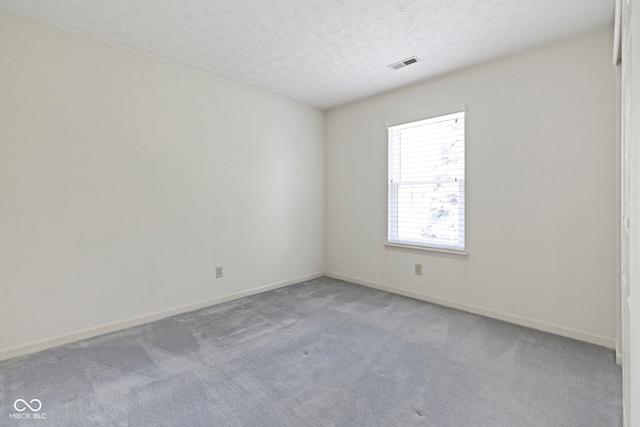 empty room featuring baseboards, visible vents, a textured ceiling, and light colored carpet