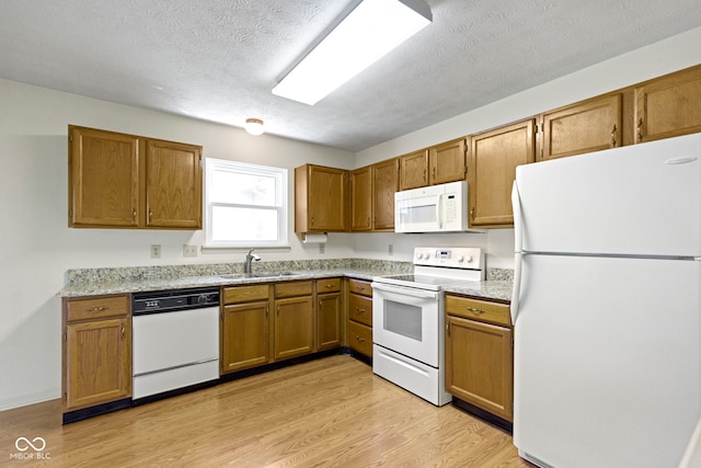 kitchen featuring a sink, brown cabinets, and white appliances
