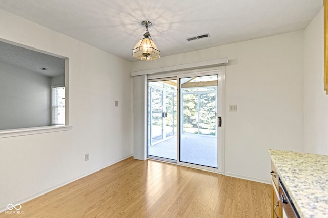 unfurnished dining area featuring visible vents, light wood-style flooring, plenty of natural light, and baseboards