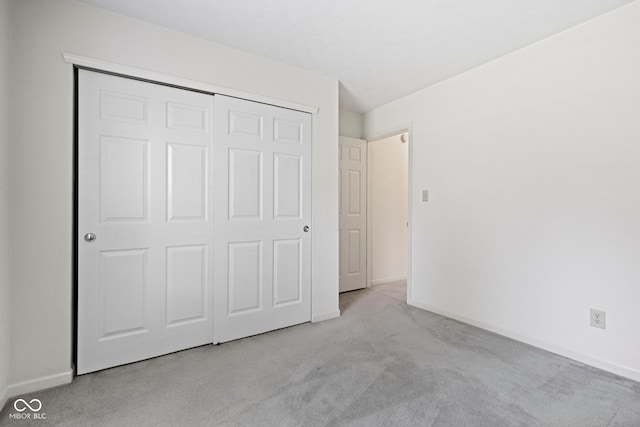 unfurnished bedroom with baseboards, carpet, and a closet