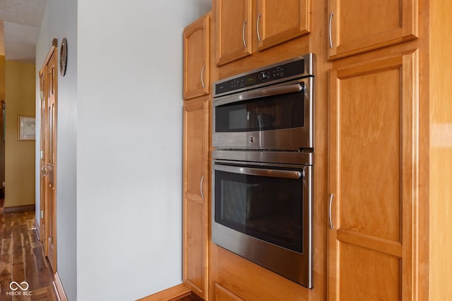 kitchen with visible vents, baseboards, dark wood-type flooring, and double oven