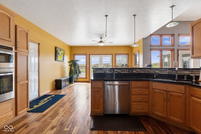 kitchen with appliances with stainless steel finishes, dark wood-style floors, ceiling fan, and a sink