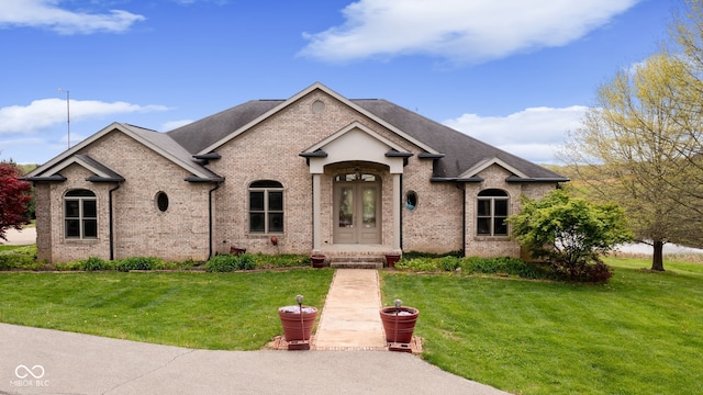 view of front of property with a front lawn, brick siding, and a shingled roof