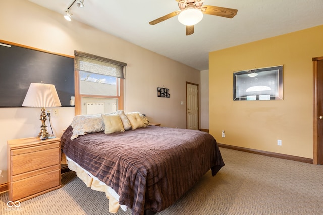 bedroom featuring rail lighting, baseboards, ceiling fan, and carpet