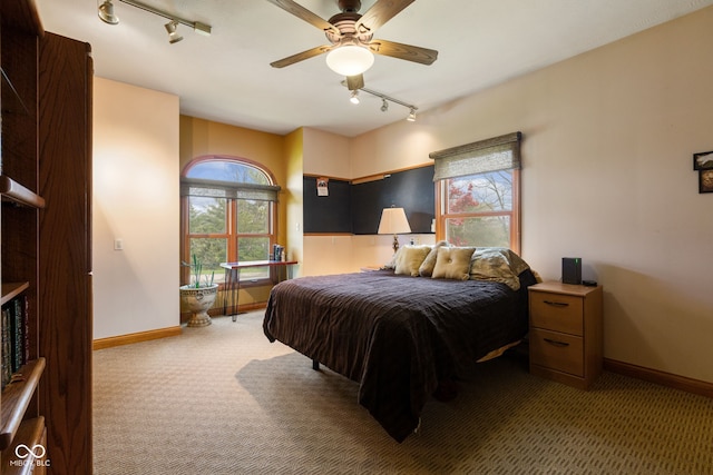 carpeted bedroom with track lighting and baseboards