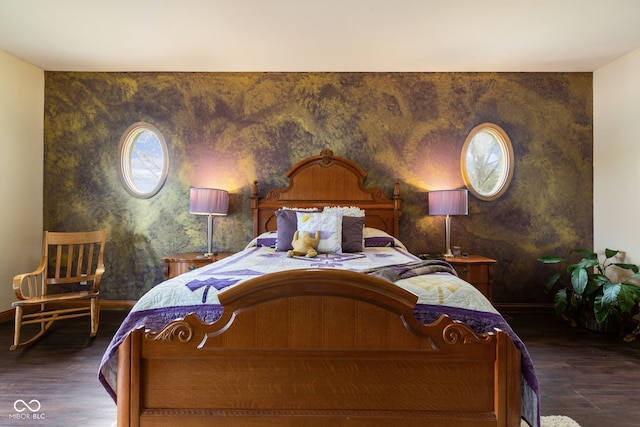 bedroom featuring an accent wall, wood finished floors, baseboards, and multiple windows
