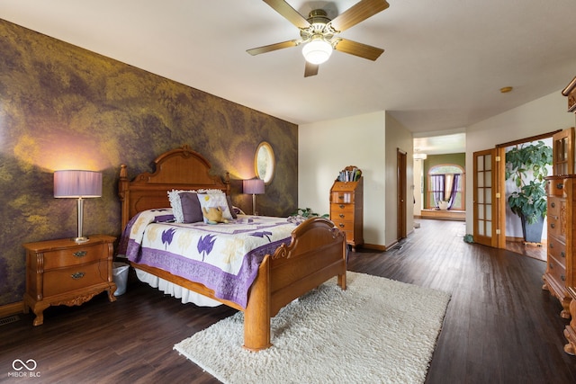 bedroom featuring an accent wall, wood finished floors, a ceiling fan, and baseboards