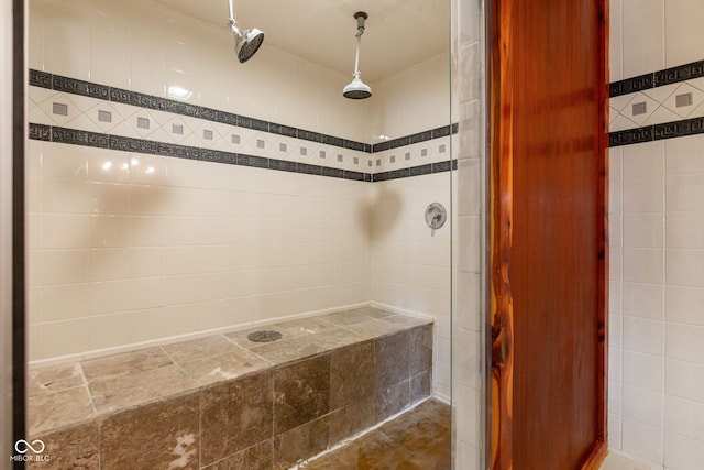 full bathroom with a tile shower and tile walls