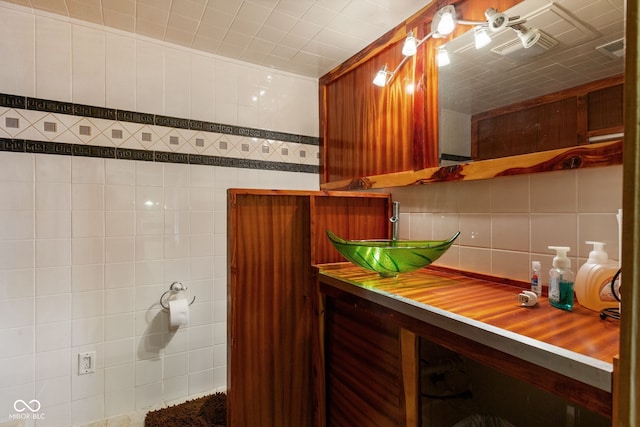 bathroom with decorative backsplash, a sink, and tile walls