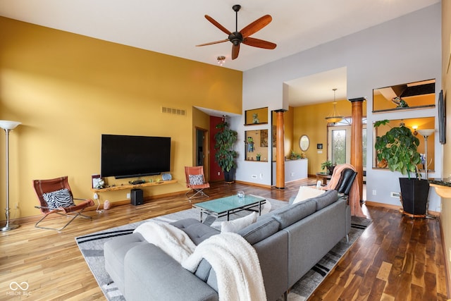 living area with wood finished floors, visible vents, high vaulted ceiling, and ceiling fan