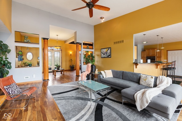living area featuring vaulted ceiling, baseboards, visible vents, wood finished floors, and ceiling fan
