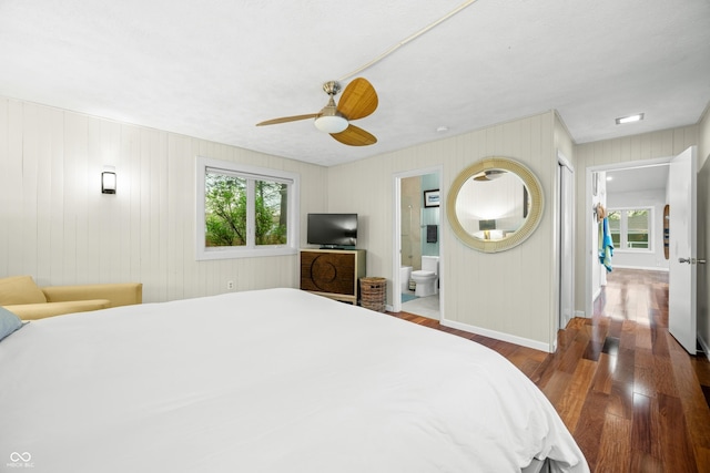 bedroom featuring baseboards, ceiling fan, wood finished floors, and ensuite bath