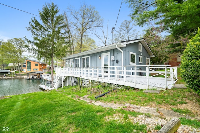 back of house featuring a lawn, board and batten siding, and a deck with water view