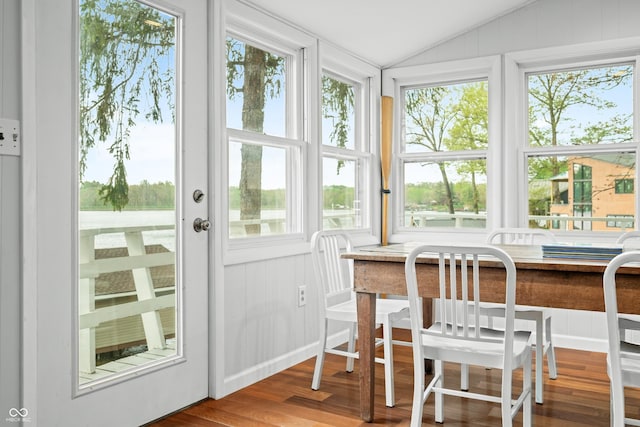 sunroom with plenty of natural light, wood finished floors, and vaulted ceiling