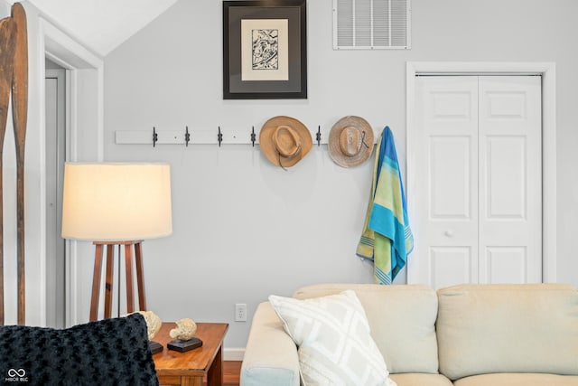 living area featuring baseboards, lofted ceiling, and visible vents