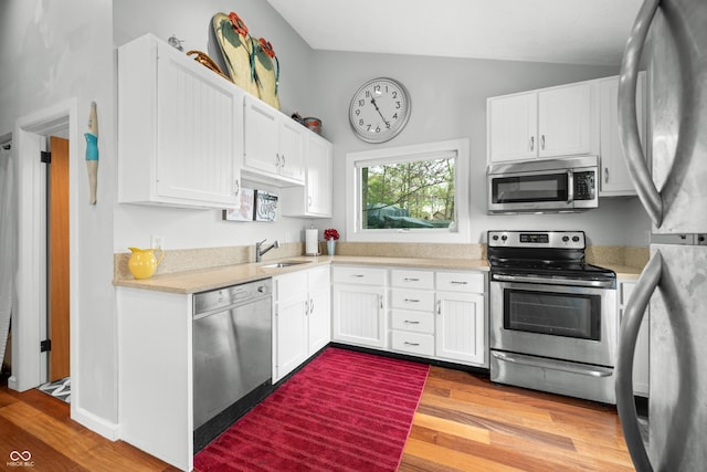 kitchen with light countertops, stainless steel appliances, light wood finished floors, and a sink