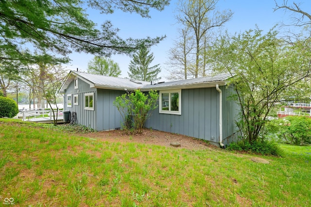 view of side of property featuring a lawn, board and batten siding, and metal roof