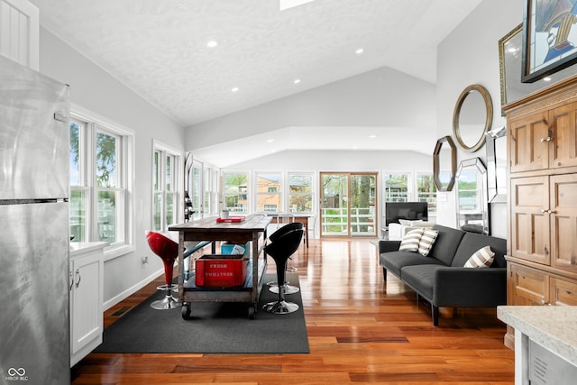 dining space with recessed lighting, a textured ceiling, light wood-style flooring, and vaulted ceiling