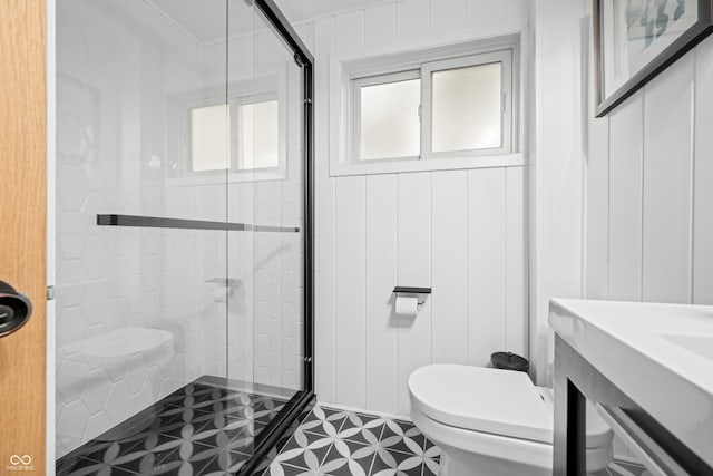 full bathroom with toilet, a shower stall, and a decorative wall