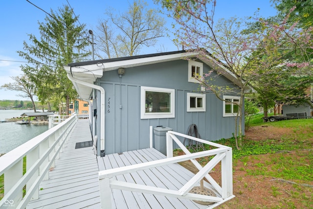 back of house with a deck with water view and board and batten siding