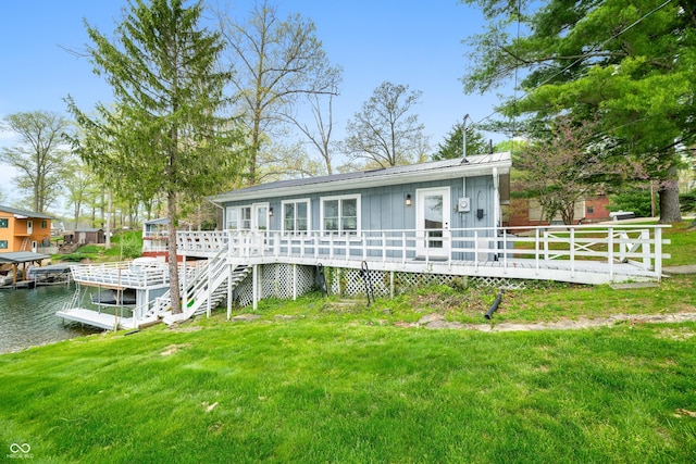 view of front of property featuring a deck with water view, board and batten siding, metal roof, and a front yard
