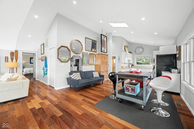 living area with vaulted ceiling with skylight, visible vents, wood finished floors, baseboards, and recessed lighting