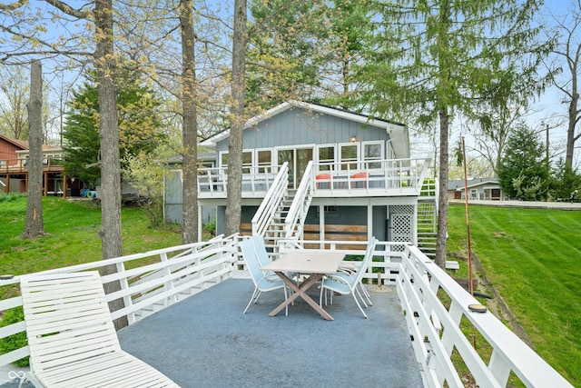 back of property featuring a wooden deck, stairs, board and batten siding, and a lawn