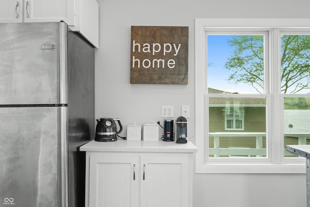 interior space featuring light countertops, freestanding refrigerator, and white cabinetry