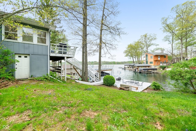 dock area with a deck with water view, a yard, and stairway