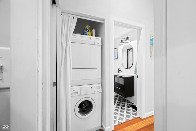 laundry area with stacked washing maching and dryer, light wood-style floors, and laundry area