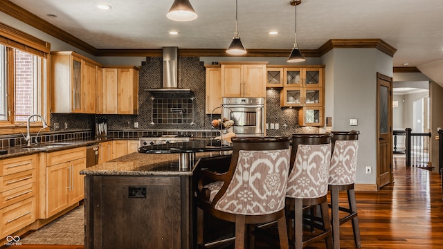 kitchen featuring light brown cabinets, a sink, crown molding, stainless steel oven, and a breakfast bar area