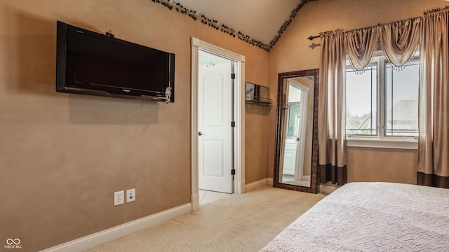 bedroom with light colored carpet, lofted ceiling, and baseboards