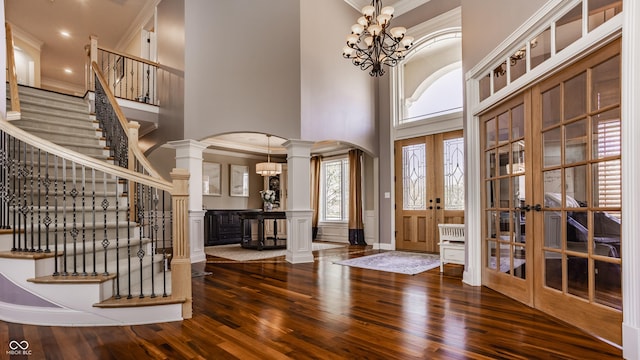 foyer with arched walkways, ornamental molding, french doors, and a towering ceiling