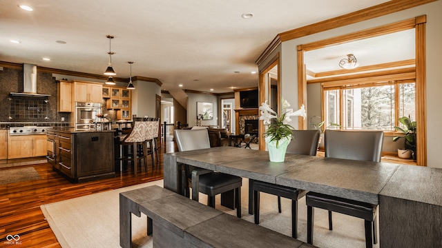 dining area featuring dark wood-type flooring, a fireplace, crown molding, and recessed lighting