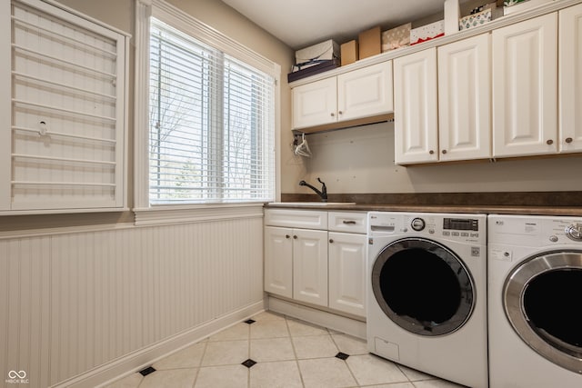 laundry room with a sink, wainscoting, independent washer and dryer, cabinet space, and light tile patterned floors