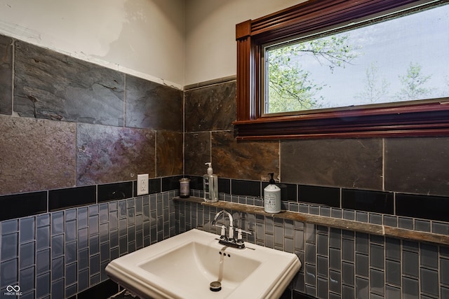 bathroom featuring tile walls, decorative backsplash, and a sink