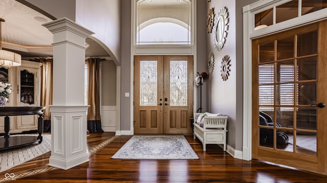 foyer featuring decorative columns, baseboards, arched walkways, and dark wood-type flooring