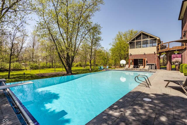 view of swimming pool featuring a diving board, a covered pool, a patio area, a deck, and a sunroom