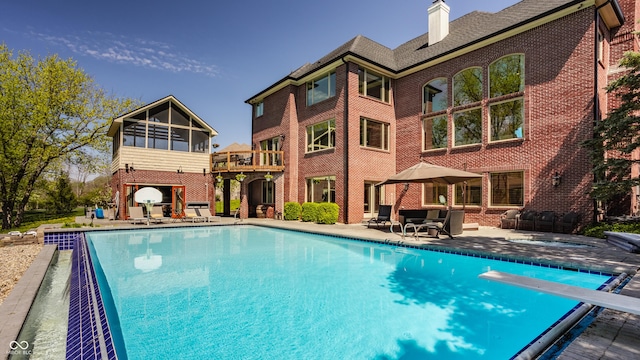 outdoor pool featuring a diving board and a patio