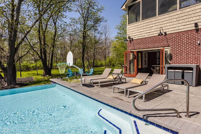 pool featuring a sunroom and a patio area