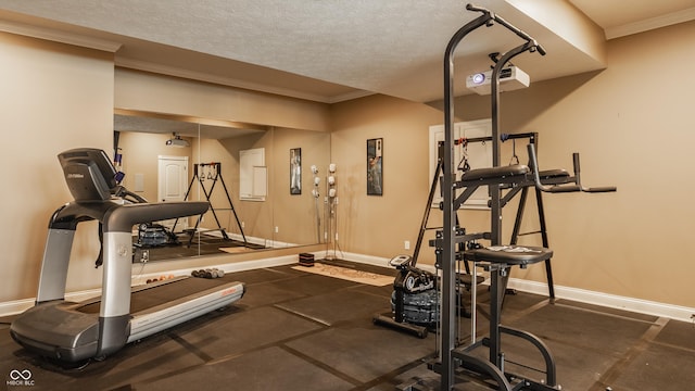 exercise area with a textured ceiling, baseboards, and ornamental molding